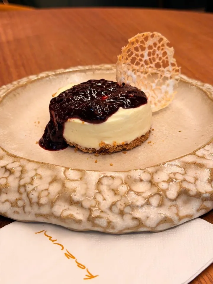 Cheesecake com calda de frutas vermelhas sobre prato artesanal